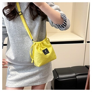 Shoulder shot of a bright yellow drawstring bucket bag with a branded square patch