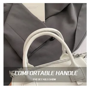 Detail of the dual cylindrical handles and reinforced cross-stitching on the white handbag