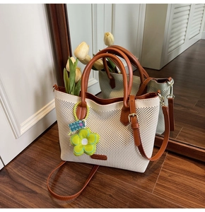 Détail du sac fourre-tout en maille crème avec poignées en cuir et charm fleur