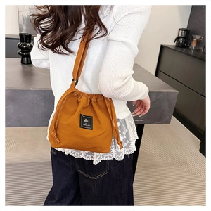 Detail of caramel drawstring bucket bag featuring contrast stitching and black label