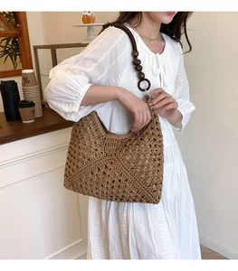 Detail of straw woven tote with dark brown straps and decorative wooden beads