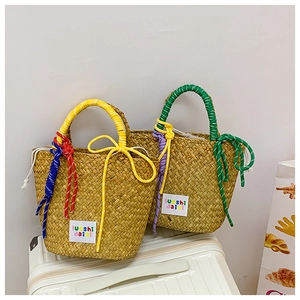 Close-up of woven straw handbag with colorful rope handles and brand fabric label