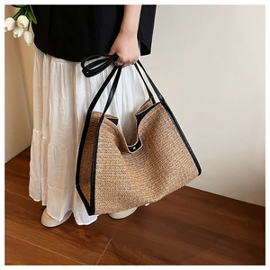 Detail of woven straw tote bag with black leather trim and herringbone texture