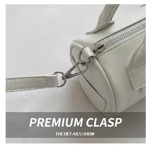 Detail of silver metal hook and white leather strap on a vintage cylinder handbag