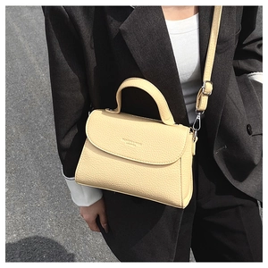 Détail du cuir à grain lychee de qualité et logo de mode sur le sac bandoulière beige