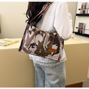 Detail of the camouflage tote bag with leather logo patch and adjustable wide strap