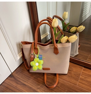 Détail du grand sac cabas en tricot avec garniture en similicuir brun et breloque fleur