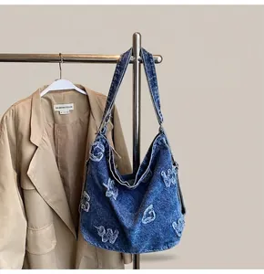 Detail view of large denim tote with vintage wash and distressed letter embroidery