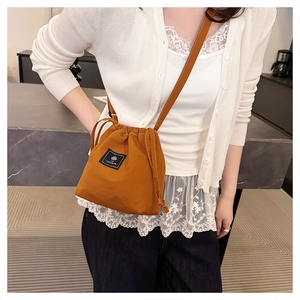 Detail of orange drawstring bucket bag with branded label and textured nylon fabric