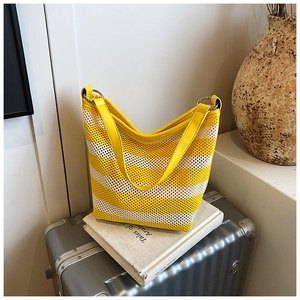 Detail of yellow and white striped woven tote bag with leather handles and metal rings