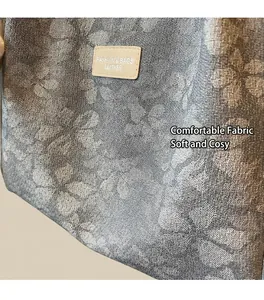 Detail of grey-blue floral jacquard weave fabric and leather logo patch on shoulder bag