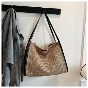 Close-up of woven straw tote bag featuring a V-shaped texture and black leather shoulder straps
