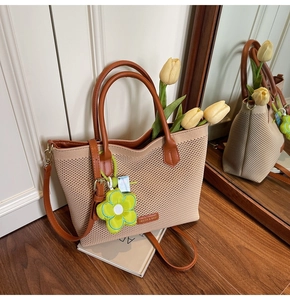 Détail du sac cabas en tricot avec anses en cuir et breloque fleurie verte