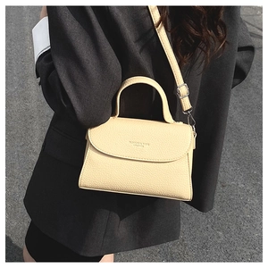 Détail du sac bandoulière beige en cuir avec lettrage mode et boucles métalliques