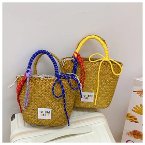 Detail of woven straw tote bags in yellow and blue with decorative knot and drawstring closure