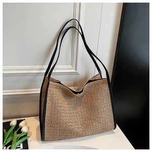 Close-up of woven herringbone straw texture with black leather strap on a tote bag