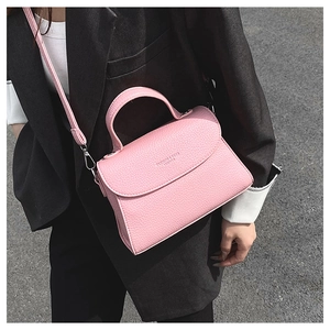 Sac bandoulière rose en cuir grainé porté sur un blazer noir dans un style urbain