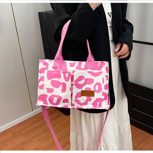 Detail view of pink and white leopard print tote bag with brown leather TXBD patch and pockets