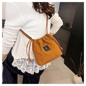 Caramel drawstring bucket bag in lightweight fabric shown in a stylish lifestyle setting