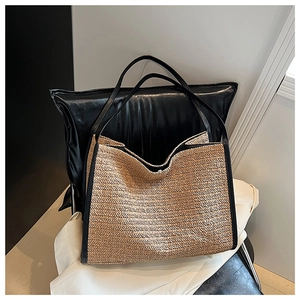 Detail of woven straw tote bag featuring black leather trim and herringbone texture
