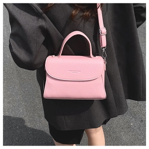 Détail du sac à bandoulière en cuir rose grainé avec sangle réglable et texte embossé