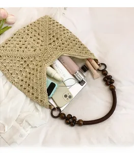 Macro detail of straw tote bag showing hollow weave texture and brown wooden bead handle