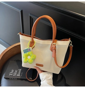 Détail du sac cabas tissé crème avec anses en cuir marron et pendentif fleur