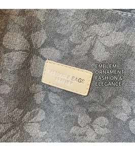 Detail of floral canvas tote bag showing the leather logo tag and fabric texture