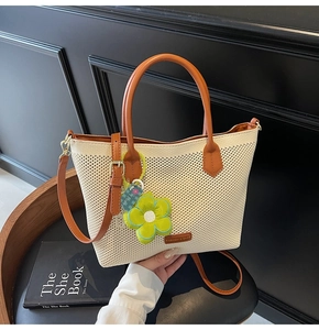 Détail du cabas tissé blanc cassé avec poignées en cuir et charm floral vert vif