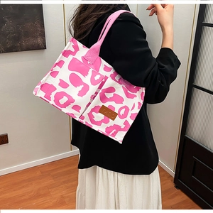 Close-up of pink leopard print tote bag with premium leather brand patch detail