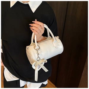 Dettaglio della borsa a cilindro bianca con ciondolo a cuore e fiocco in nastro