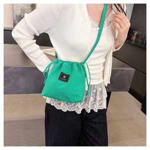 Crossbody drawstring bucket bag in grass green nylon fabric with logo patch
