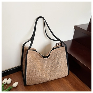 Detail of herringbone straw weave and black leather strap on a large beach tote bag