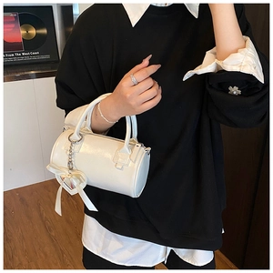 Elegante borsa a cilindro bianca con ciondolo a cuore in un ambiente lifestyle curato
