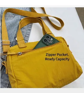 Détail du sac en toile jaune montrant la poche zippée avant et sa capacité de stockage