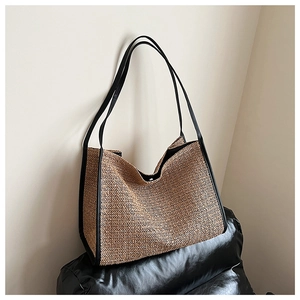 Detail shot of woven straw tote bag with black leather trim and herringbone pattern texture
