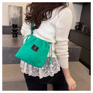 Close-up of bright green drawstring bucket bag showing the texture and brand label