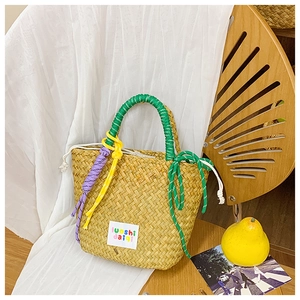 Detailed view of the woven straw tote bag with green rope handles and drawstring closure