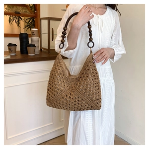 Detail of woven straw shoulder bag with vintage dark wood bead handle in cafe setting