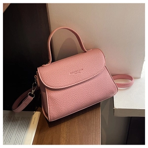 Détail du sac bandoulière rose en cuir grainé avec texte Fashion & Bags embossé