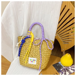 Detail of hand-woven straw bag with colorful braided handles and a stylish label logo