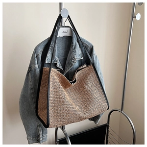Detail of herringbone straw weave texture and black shoulder strap on large tote bag