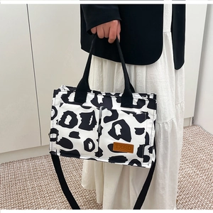 Close-up of zebra print tote bag featuring black woven handles and brown leather TXBD logo tag
