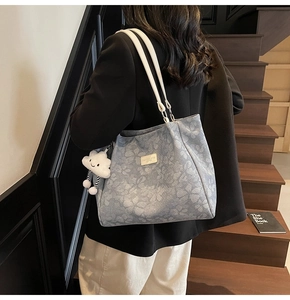 Détail du sac cabas floral bleu clair avec un charm nuage blanc sur un fond en bois sombre