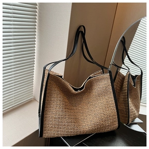 Detail view of woven straw tote bag with black leather trim and long shoulder straps