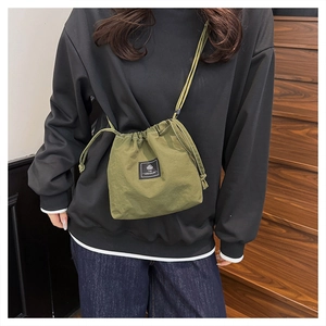 Detail of army green nylon bucket bag featuring drawstring closure and brand label