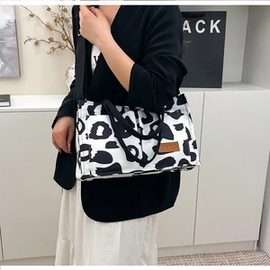 Fashionable canvas tote bag with cow print pattern shown on a stylish model outfit
