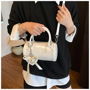 Borsa a cilindro bianca con ciondolo a cuore indossata in stile casual urbano da modella