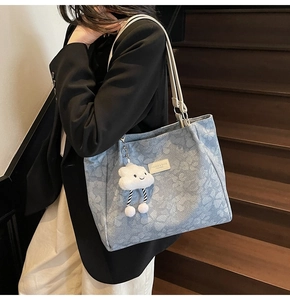 Détail du cabas en jacquard bleu clair avec étiquette en cuir et breloque peluche