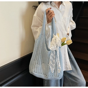 Detail of light blue knit tote bag with mesh texture and white lace bow decoration